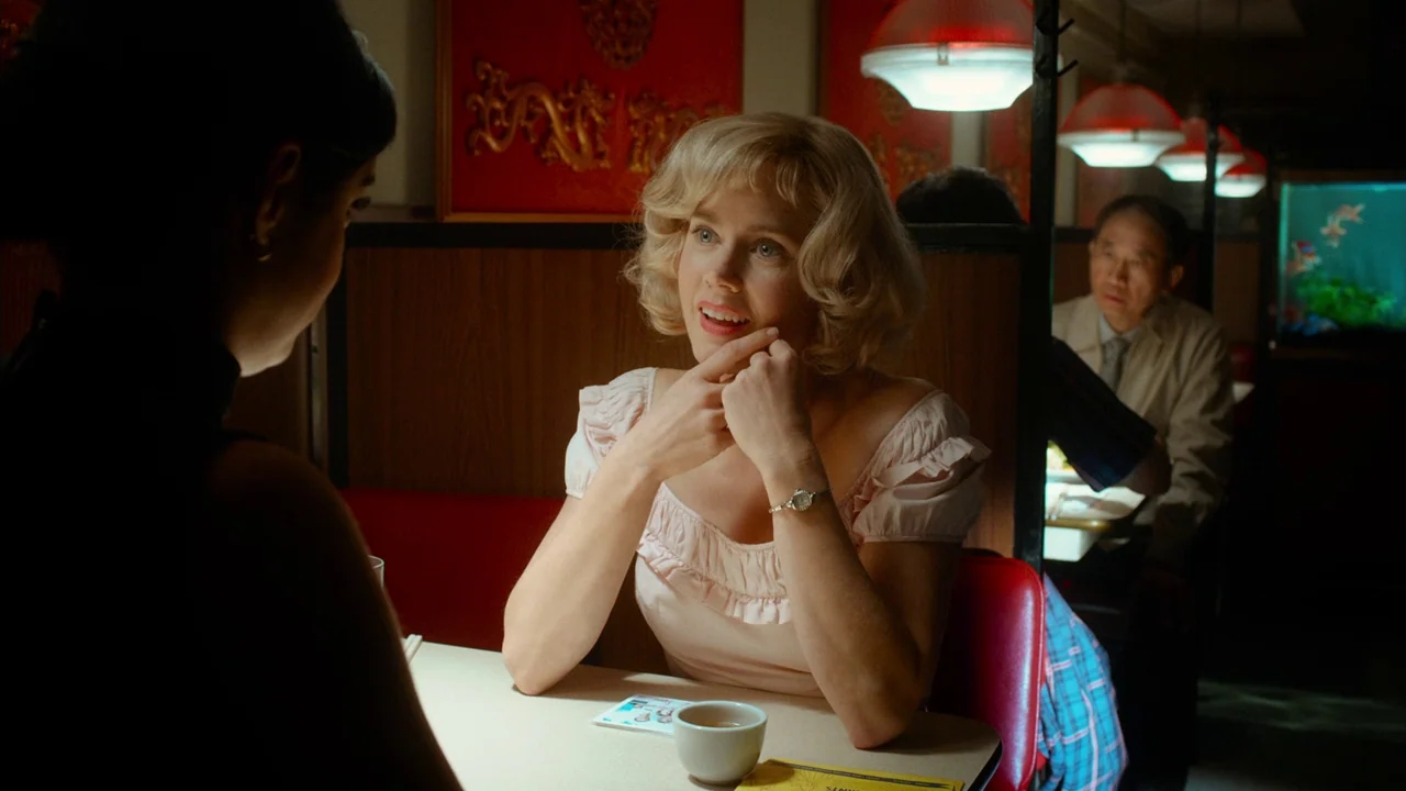 Big Eyes (2014) movie still: medium — A dimly lit diner booth features wood-paneled walls decorated with red Asian-style wall art. A woman with…