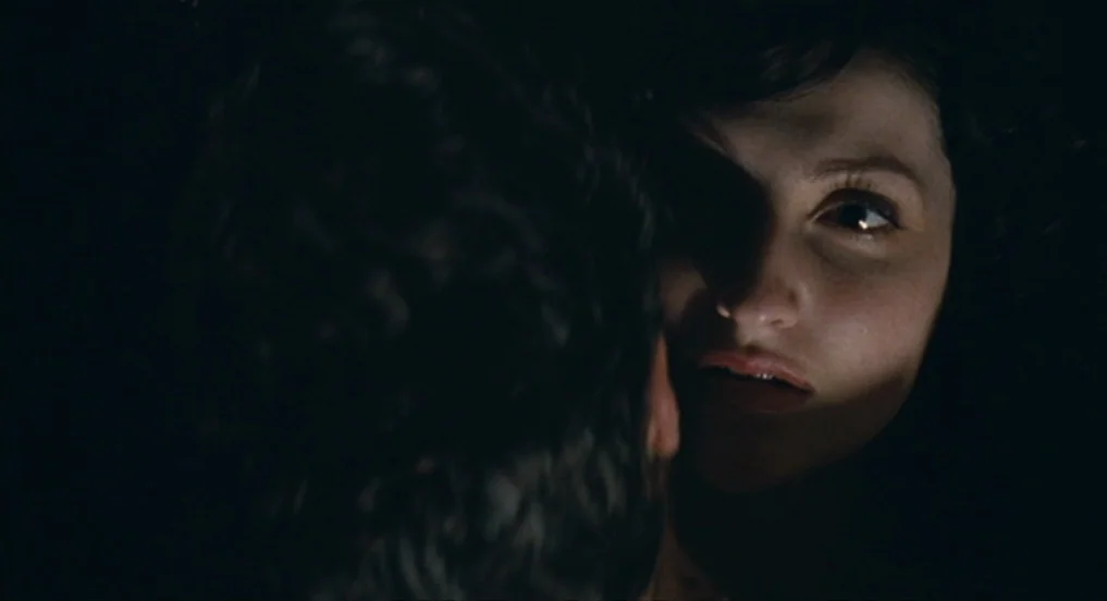 House of Tolerance (2011) movie still: closeup — An interior space is enveloped in near-total darkness. A woman is lit partially while facing a man…