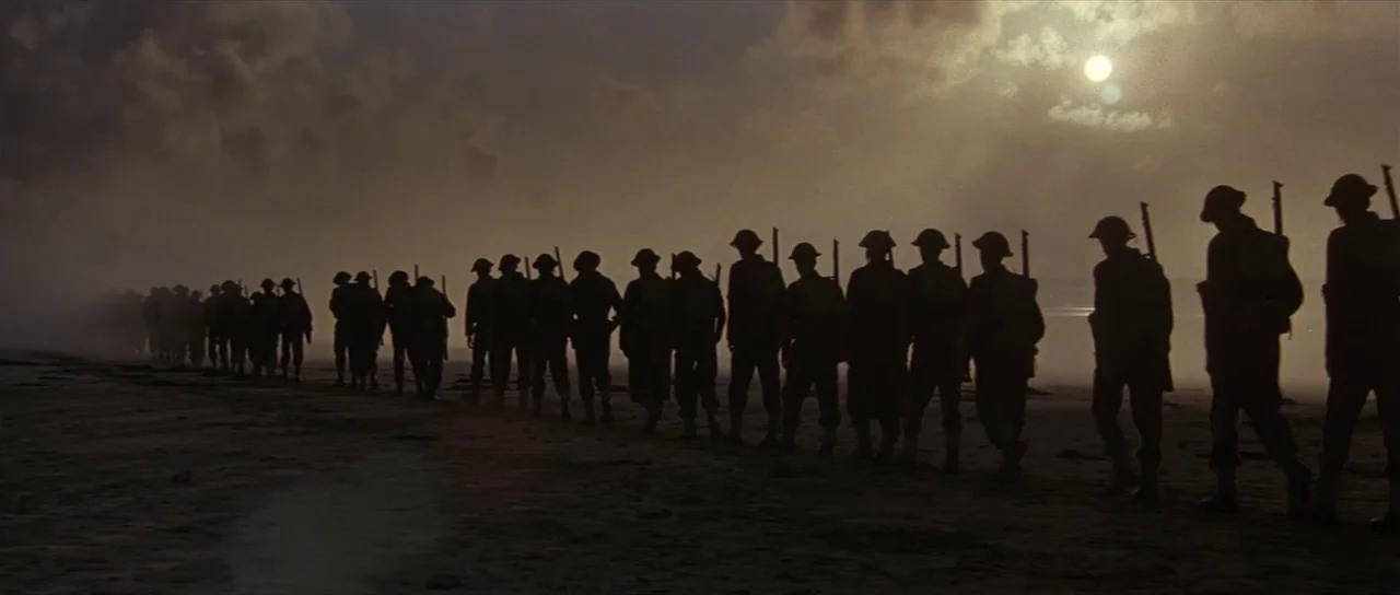Pink Floyd The Wall (1982) movie still: wide — A long line of soldiers walks across a misty beach under a bright sky. The group moves together in…