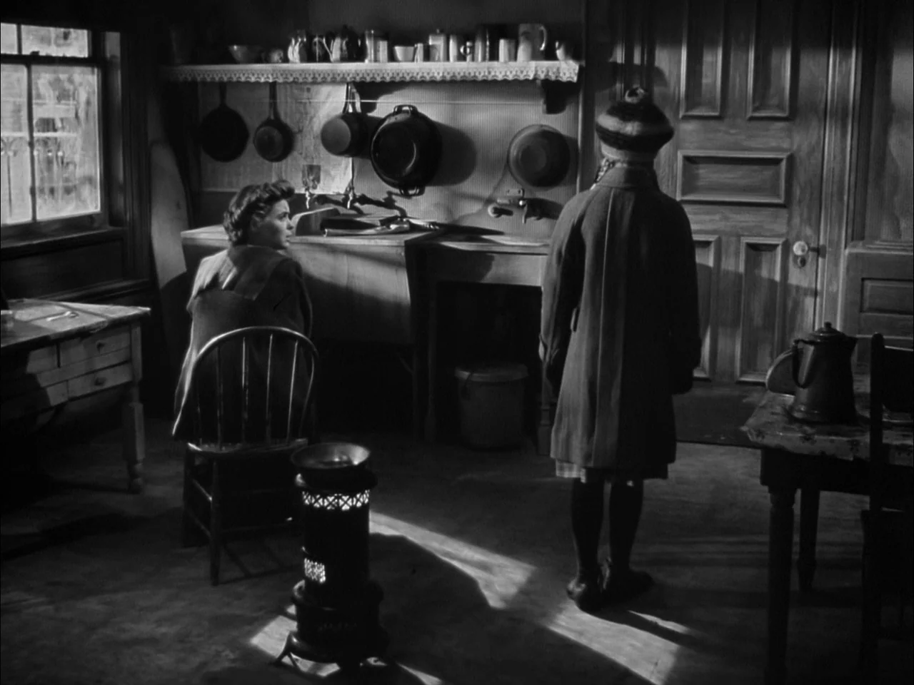 A Tree Grows In Brooklyn (1945) movie still: fullbody — A dark, rustic interior features a wooden basin and various pots hung on the wall. A woman…