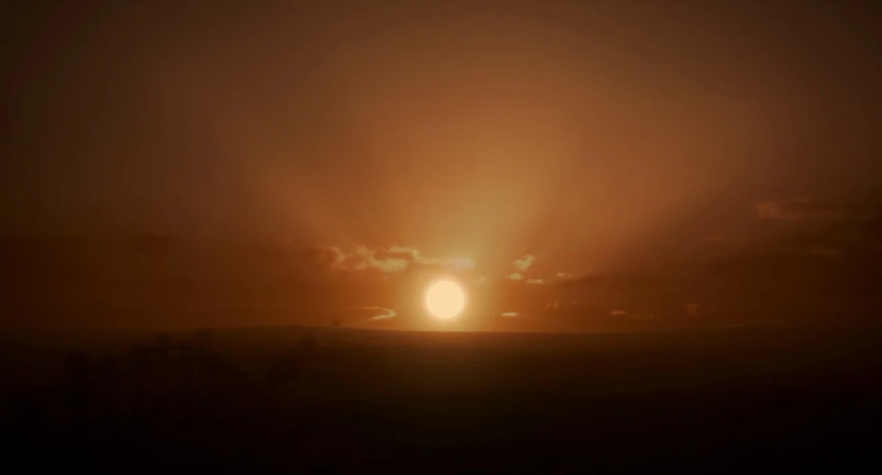 The Ballad of Buster Scruggs (2018) movie still: establishing — The horizon is illuminated by a low-hanging sun amidst dark, scattered cloud…