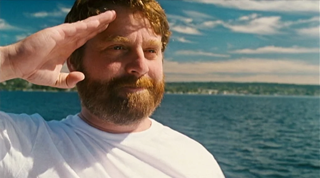 Visioneers (2008) movie still: closeup — A man stands on a boat on a large body of water. The subject salutes while looking toward the distant…