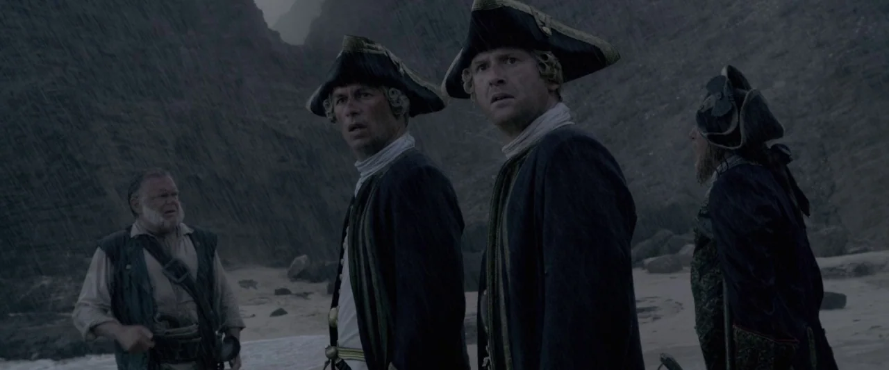 Pirates of the Caribbean: On Stranger Tides movie still: medium — A group of men in 18th-century military dress stand on a rainy, rocky beach. The…