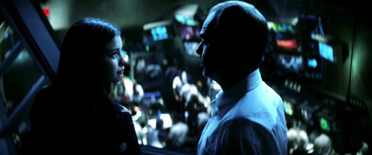 Armageddon (1998) movie still: medium — A dark NASA mission control center is filled with rows of glowing monitors and consoles. A man and a woman…
