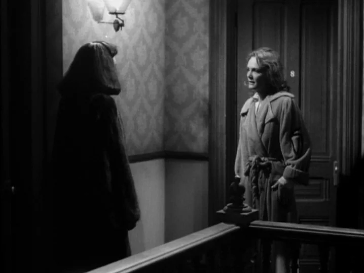 The Seventh Victim (1943) movie still: medium — An apartment hallway with patterned wallpaper and a wooden door marked with the number eight. One…
