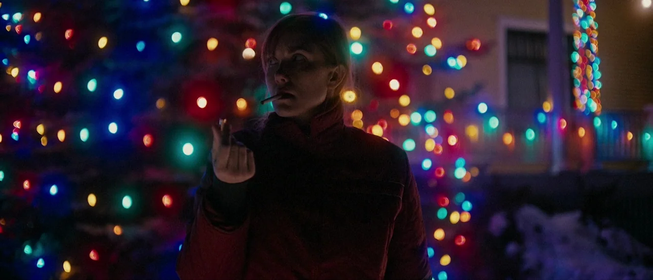 I Trapped The Devil (2019) movie still: medium — A dark outdoor space features a Christmas tree densely decorated with glowing colorful string…