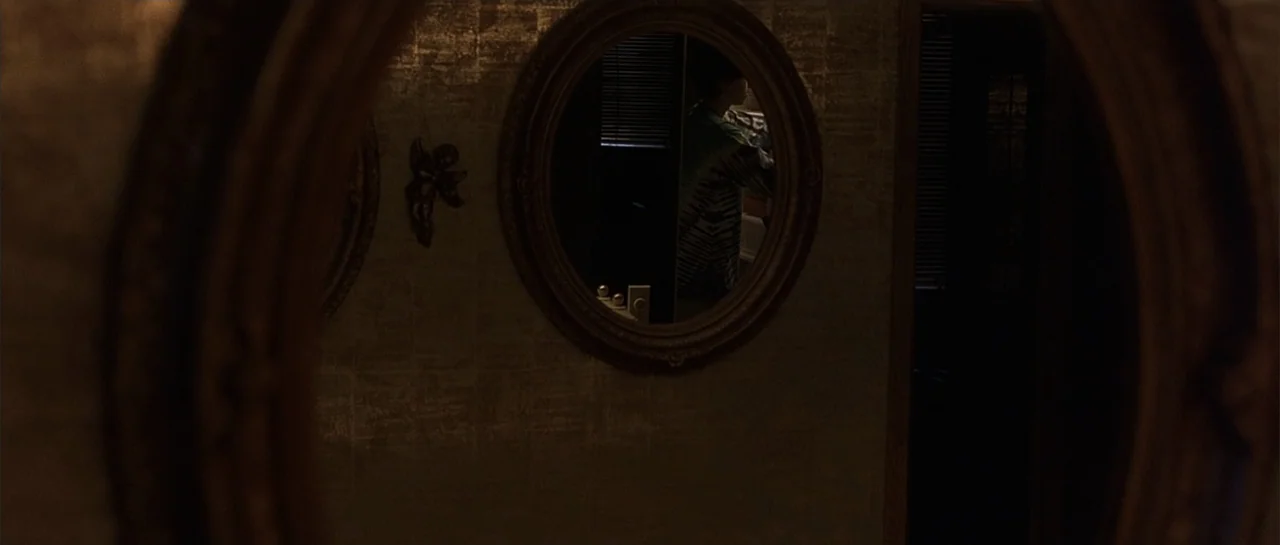 Bandits (2001) movie still: medium — A dimly lit domestic bathroom features textured wall coverings and a prominent oval wall mirror. A young man…