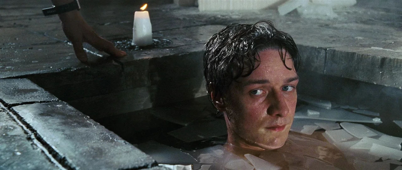 Wanted (2008) movie still: closeup — A man sits in a basin filled with water and scattered white ceramic shards. A single lit candle rests on the…