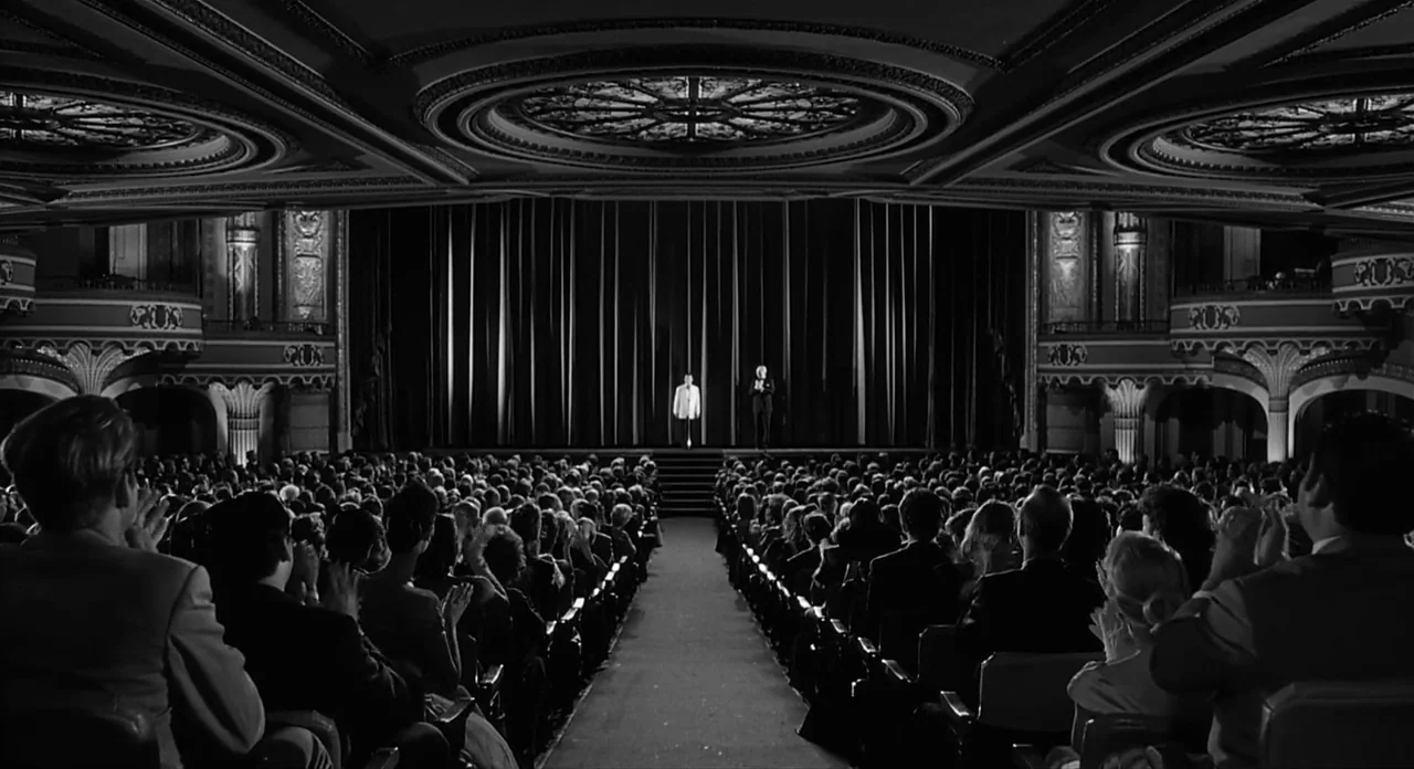 Ed Wood (1994) movie still: wide — A grand, ornately decorated theater auditorium is filled with a seated audience in darkness. Two individuals…