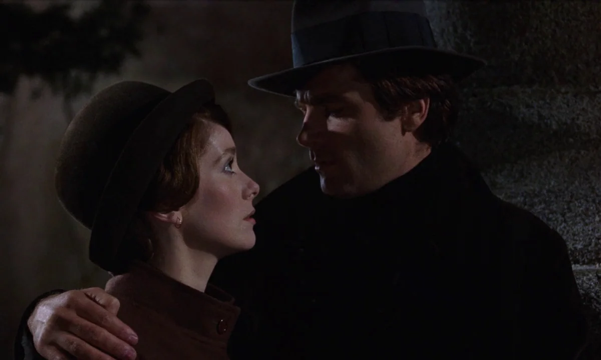 Tristana (1970) movie still: medium — A man and a woman stand together against a dark wall at night. The man keeps his arm around the woman's…