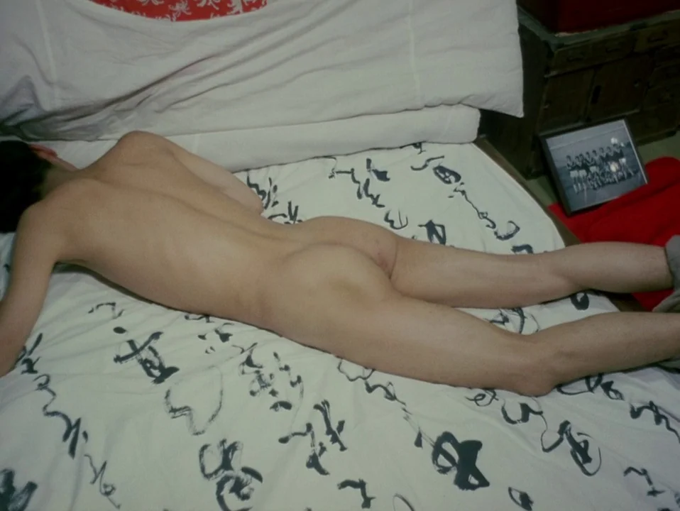 Throw Away Your Books, Rally in the Streets (1971) movie still: medium — A person lies prone on a white bedspread patterned with black calligraphy.…
