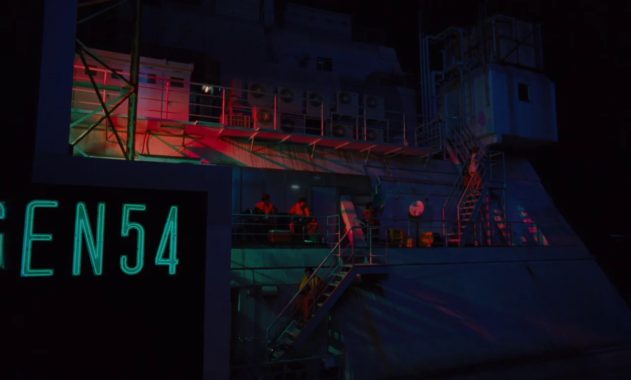 Until The End Of The World (1991) movie still: wide — An industrial structure features metal staircases, air conditioning units, and a large neon…