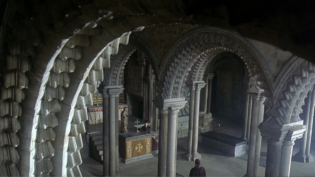 Elizabeth (1998) movie still: establishing — An expansive stone church interior features intricate vaulted arches and numerous supporting pillars.…