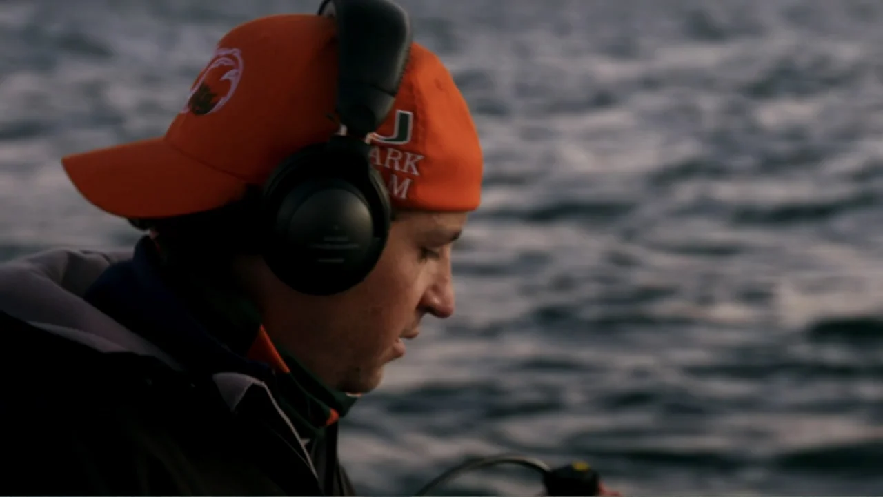 Air Jaws: Night Stalker (2016) movie still: closeup — An expanse of dark undulating water serves as a backdrop for a man. A man in an orange cap and…