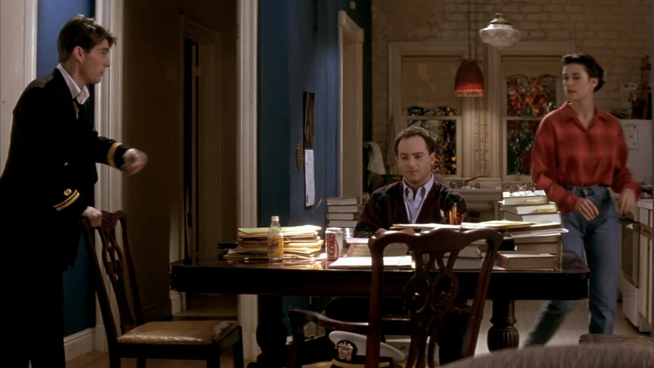 A Few Good Men (1992) movie still: medium — A residential room features a dark wood table covered in stacks of documents. Three people interact in…