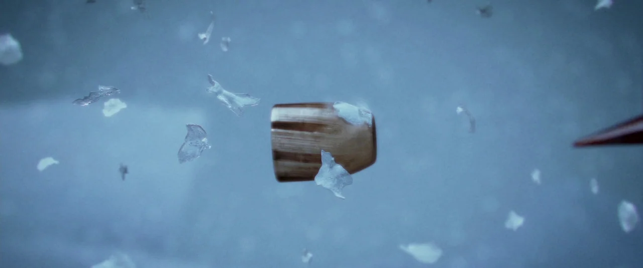 Resident Evil: Retribution (2012) movie still: closeup — A copper-jacketed bullet moves through the air amidst floating shards of transparent…