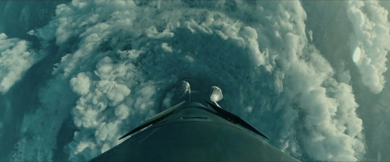 Invasion (2020) movie still: wide — A dark rocket nozzle pushes through a massive blanket of dense white cumulonimbus clouds. Sunlight hits the…