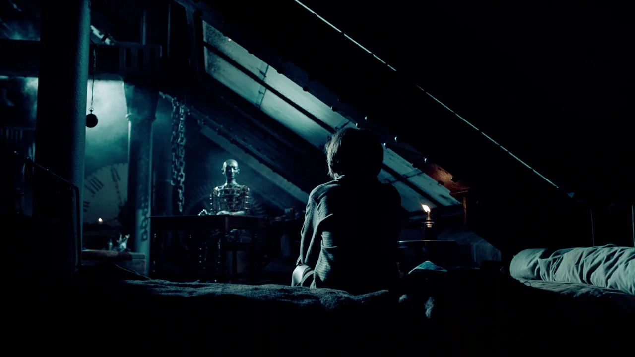 Hugo (2011) movie still: wide — A dark wooden attic with slanted ceilings, exposed structural beams, and heavy iron chains hanging. A young boy…