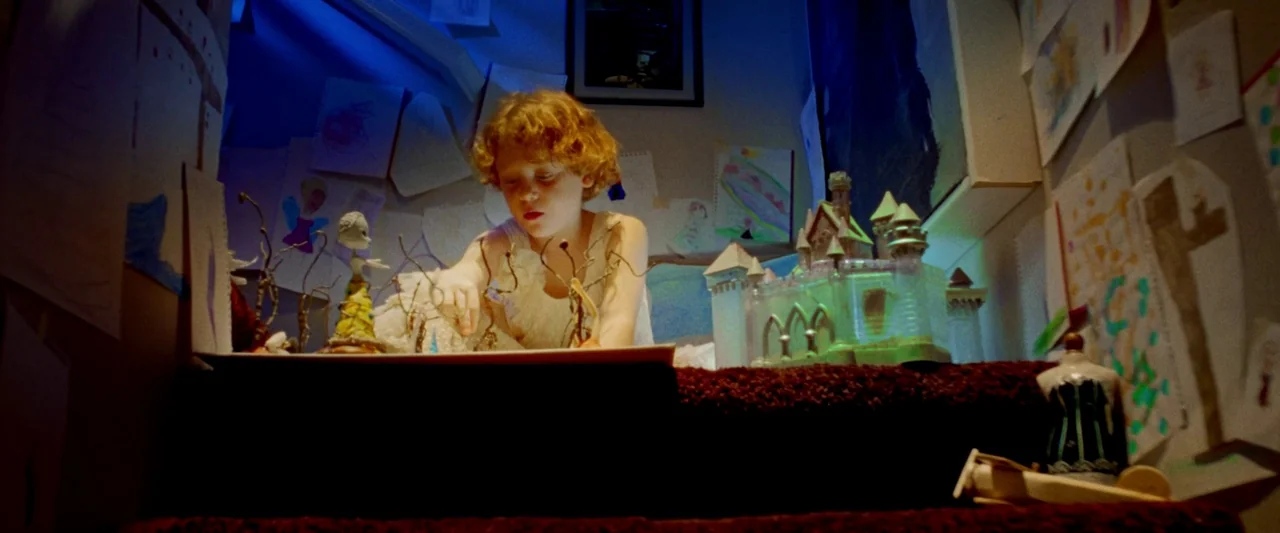 Moon Garden (2022) movie still: medium — A young child sits on a carpeted staircase surrounded by various drawings taped up. The child plays with…