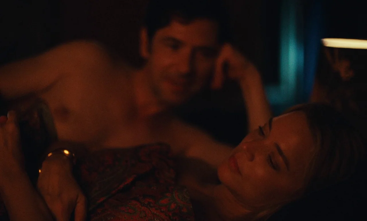 Just The Two Of Us (2023) movie still: medium — A dimly lit bedroom features two people resting close together on a surface. A man lies behind a…
