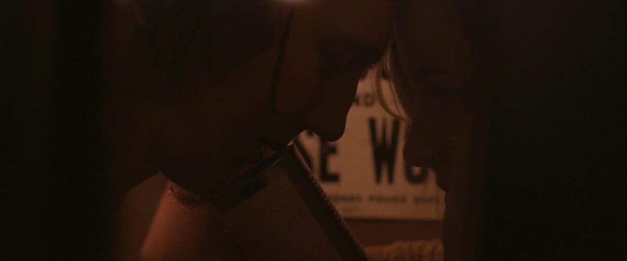 For Ellen (2012) movie still: closeup — A dimly lit room features two individuals pressing their foreheads together in close proximity. A metal tin…