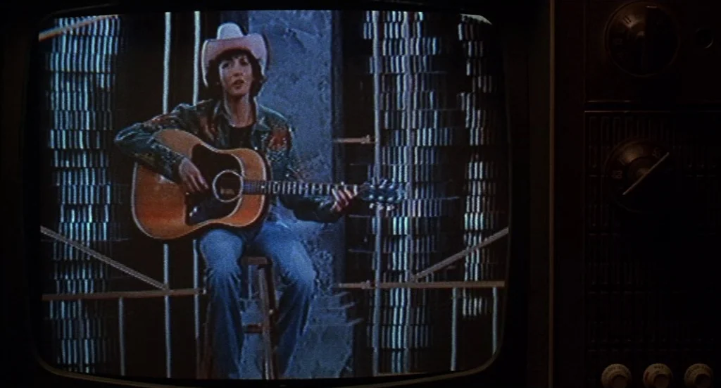 Melvin & Howard (1980) movie still: medium — The image shows a broadcast signal on a vintage CRT television set. A musician in a western outfit sits…