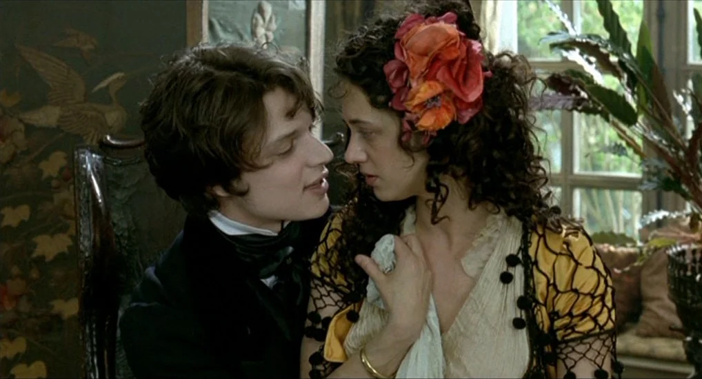 The Last Mistress (2007) movie still: medium — A 19th-century interior features patterned wallpaper and a window with potted green plants. A man and…