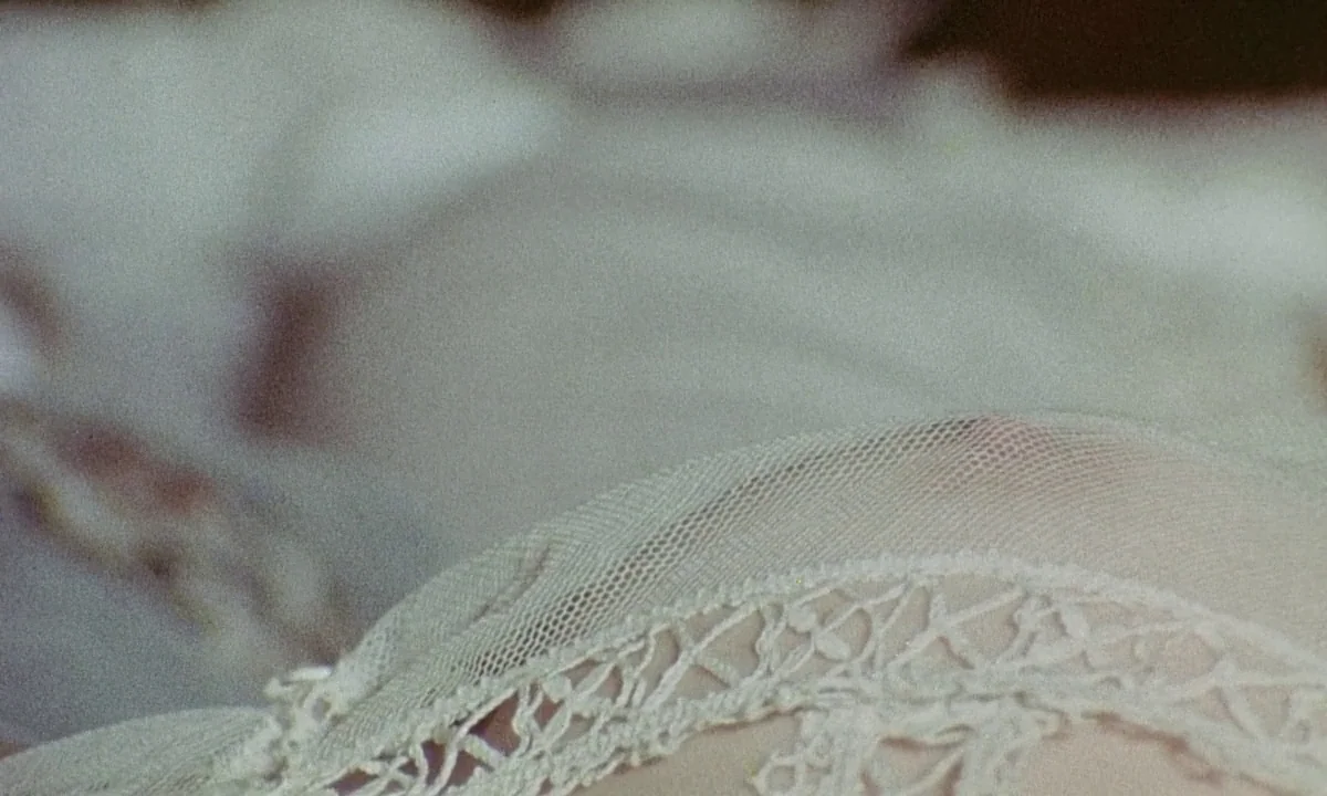 Immoral Tales (1974) movie still: closeup — A close-up view shows the intricate patterns of white vintage lace fabric. The delicate material rests…