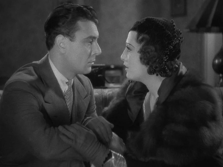 42nd Street (1933) movie still: medium — A dimly lit 1930s interior features a man and woman in formal attire. They sit across from each other in…
