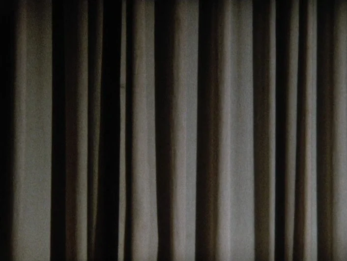 Eika Katappa (1969) movie still: establishing — A set of heavy, textured fabric curtains hangs in uniform vertical folds. The fabric completely…