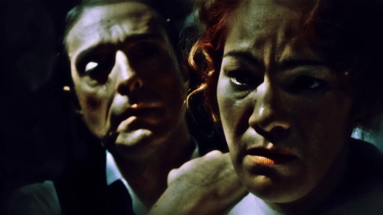 The Forbidden Room (2015) movie still: closeup — A dark, minimally lit space surrounds two individuals in close proximity. A man's hand rests on a…