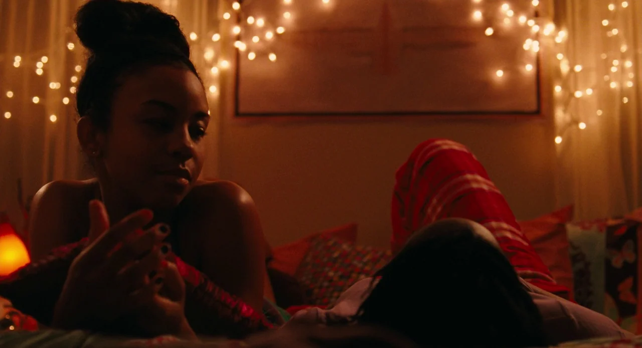 Pariah (2011) movie still: medium — Two individuals rest in a darkened room decorated with numerous illuminated white string lights. The woman in…