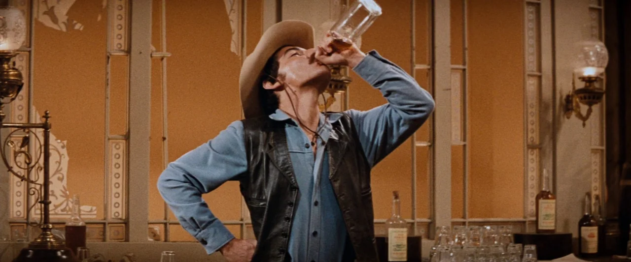 Westworld (1973) movie still: medium — An interior saloon features decorative light-colored panels with golden accents behind the bar area. A man…