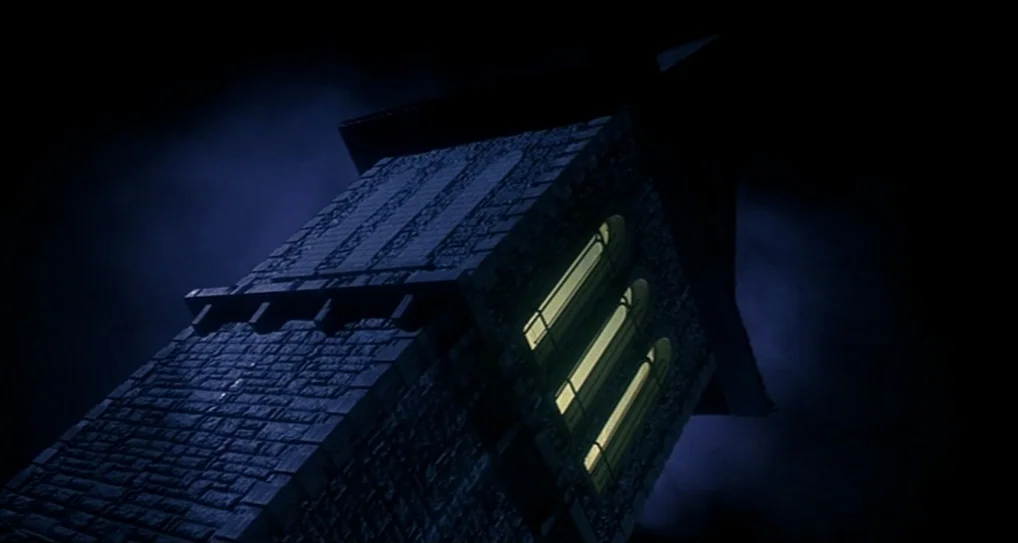 A Nightmare On Elm Street 5: The Dream Child (1989) movie still: establishing — A stone tower rises against a dark, cloudy night sky with a steep…