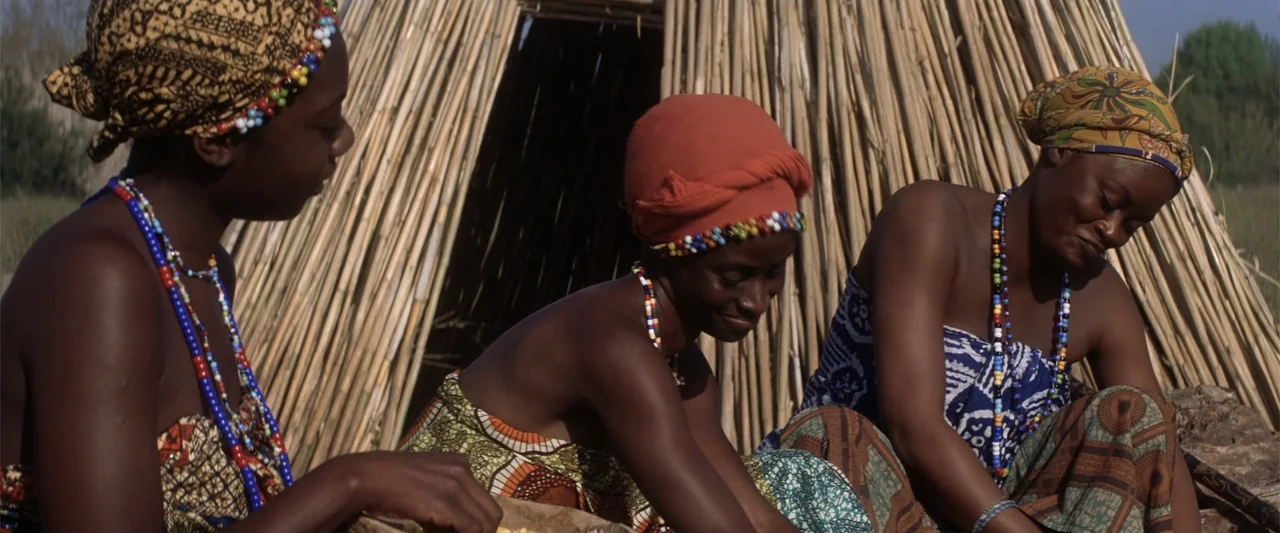 He's Just Not That Into You (2009) movie still: medium — Three women sit outside a conical thatched structure made of dried reeds. They work…