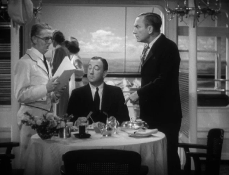 The Lady Eve (1941) movie still: medium — Three men interact inside a train dining car with large windows and white tablecloths. A waiter holds a…