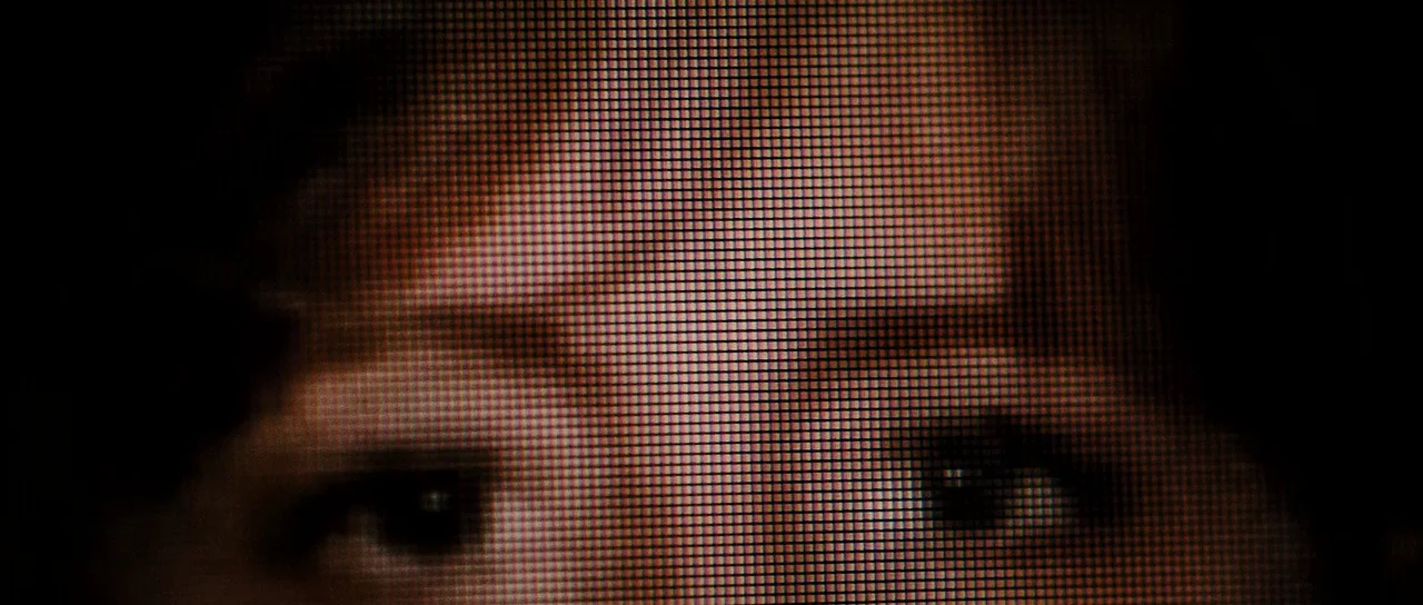 The East (2013) movie still: closeup — A close-up view of a face obscured by a dense digital pixel matrix. The image focuses on the eyes and brow…