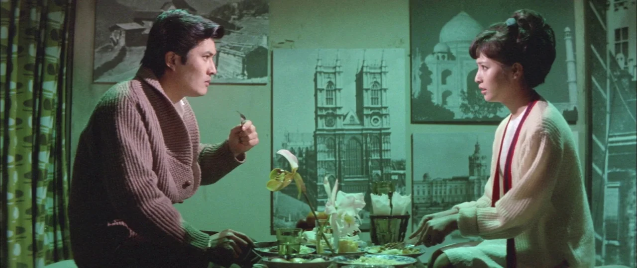 Black Tight Killers (1966) movie still: medium — A modest dining area features walls covered in large black and white architectural prints. A man…