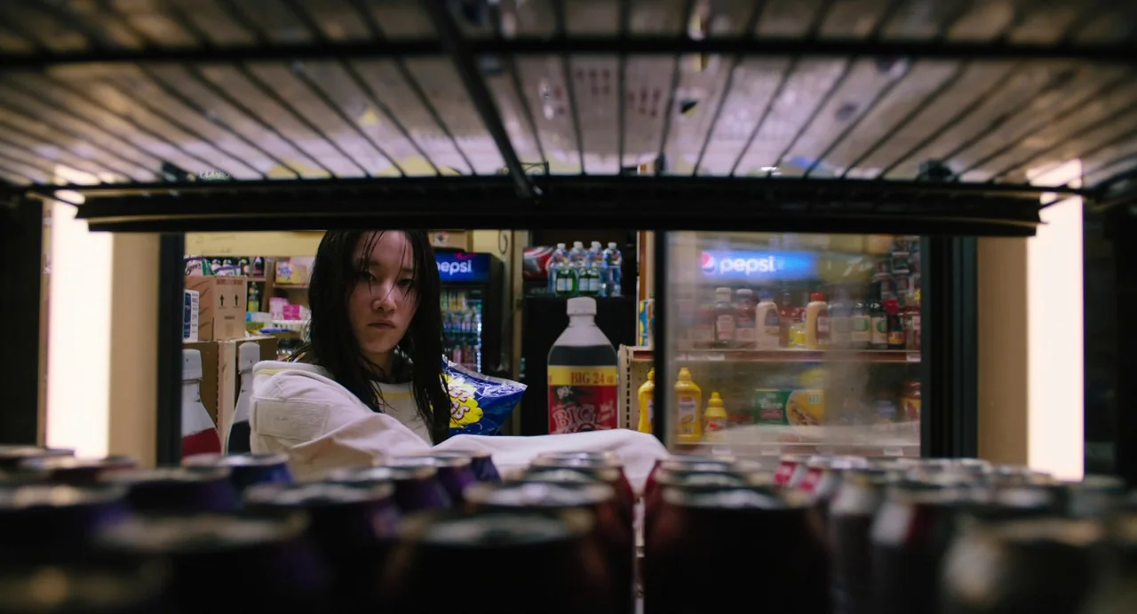 Mona Lisa and the Blood Moon (2022) movie still: medium — A dimly lit aisle in a convenience store filled with various drink products. A young woman…