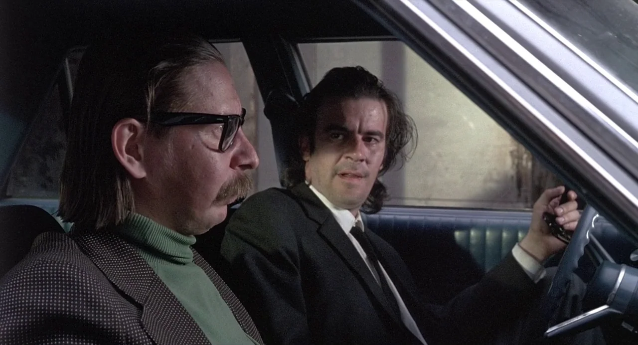 Ariel (1988) movie still: medium — The interior of a car shows two men seated in the front seats. The passenger is in profile while the driver looks…