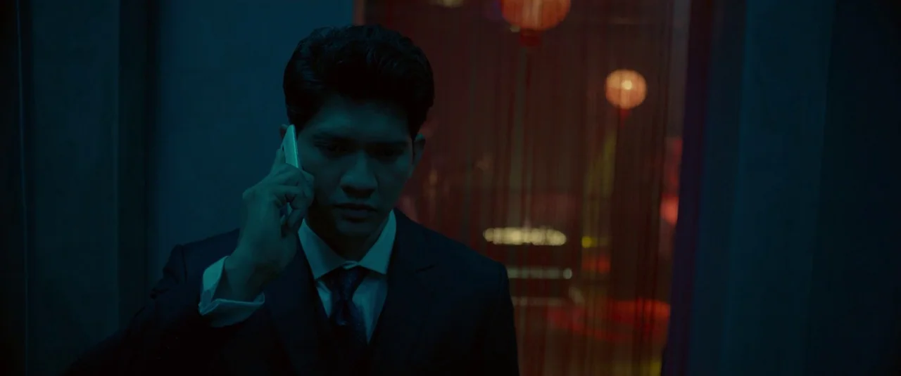 The Night Comes for Us (2018) movie still: medium — A dimly lit indoor space featuring blue ambient tones and distant glowing red paper lanterns. A…