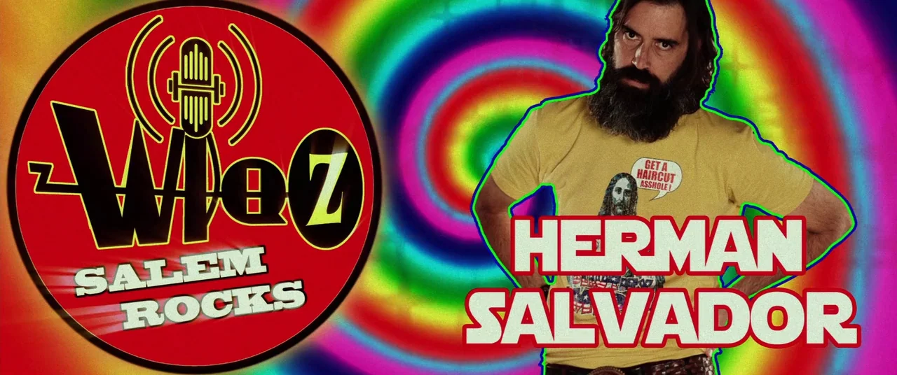 Lords Of Salem (2013) movie still: medium — A studio setting with a vibrant, hypnotic, rainbow spiral background. A bearded man stands in front of a…