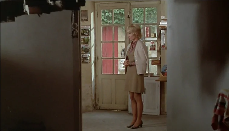 Le Boucher (1970) movie still: fullbody — A small rustic store interior features a weathered wooden-framed glass door to the outside. A young blonde…