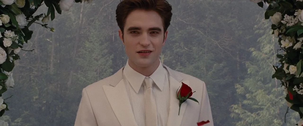 The Twilight Saga: Breaking Dawn – Part 1 (2011) movie still: medium — A man stands before a floral wedding arch in an outdoor forest setting. The…