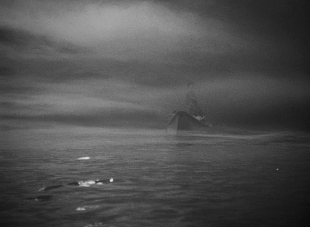 Ugetsu (1953) movie still: wide — A dark, fog-covered body of water at night under a heavy, overcast sky. A lone figure stands upright in a small…