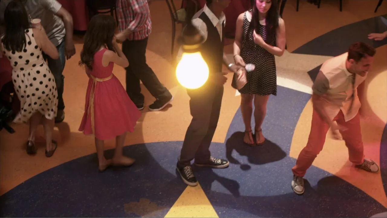 Jinxed (2013) movie still: wide — An interior dance floor features a large star-shaped floor pattern and hanging lights. Several young adults stand…