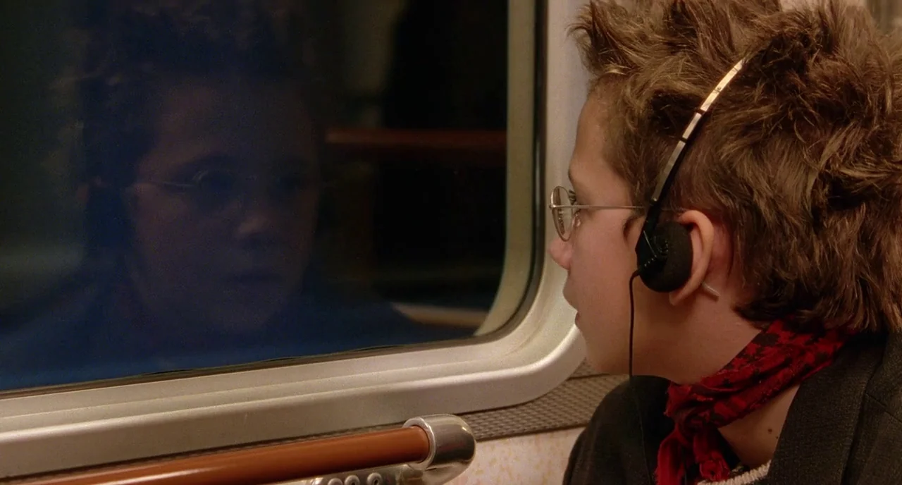We Are The Best! (2013) movie still: medium — A teenage boy rides inside a dark commuter train at night. He stares intensely at his reflection…