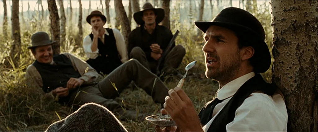 The Assassination Of Jesse James By The Coward Robert Ford (2007) movie still: medium — Four men sit among birch trees in a grove during the early…