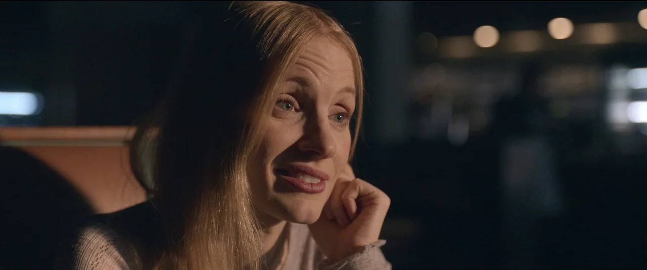 The Good Nurse (2022) movie still: closeup — A dimly lit restaurant booth at night with a blurred background. A woman sits in the booth with her…