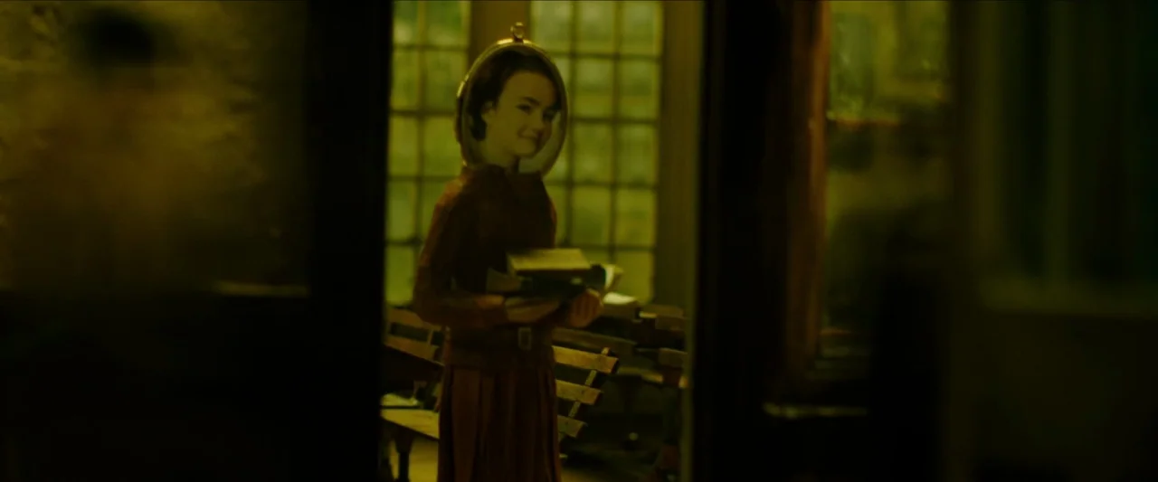 Wonderstruck (2017) movie still: medium — A dimly lit, vintage classroom features wooden desks and a large glass window pane. A girl stands in the…